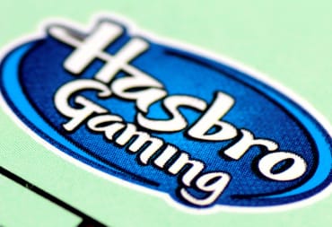 The logo for Hasbro Gaming printed on a green Monopoly board.